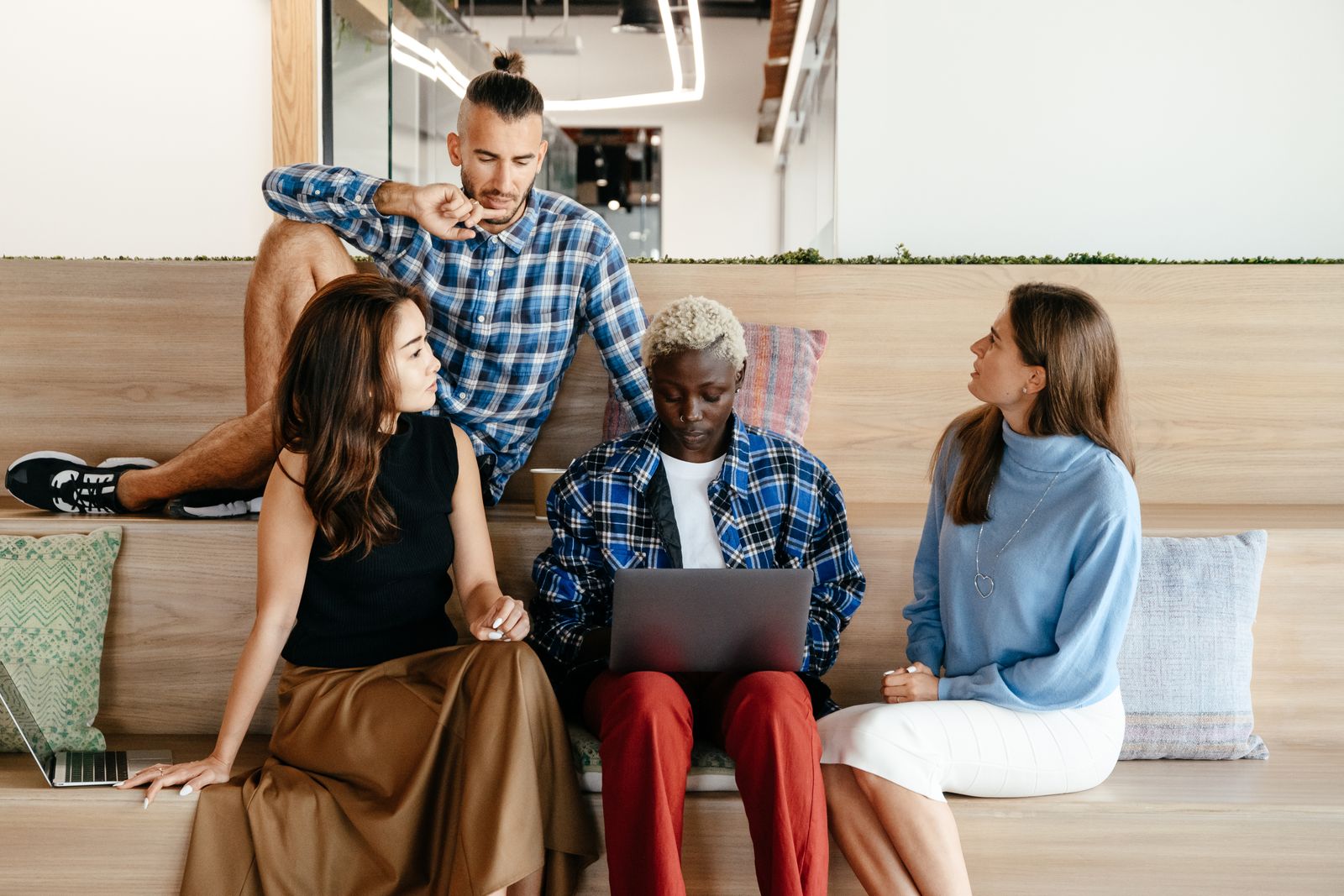 A team of colleagues collaborating around a laptop in a bright office