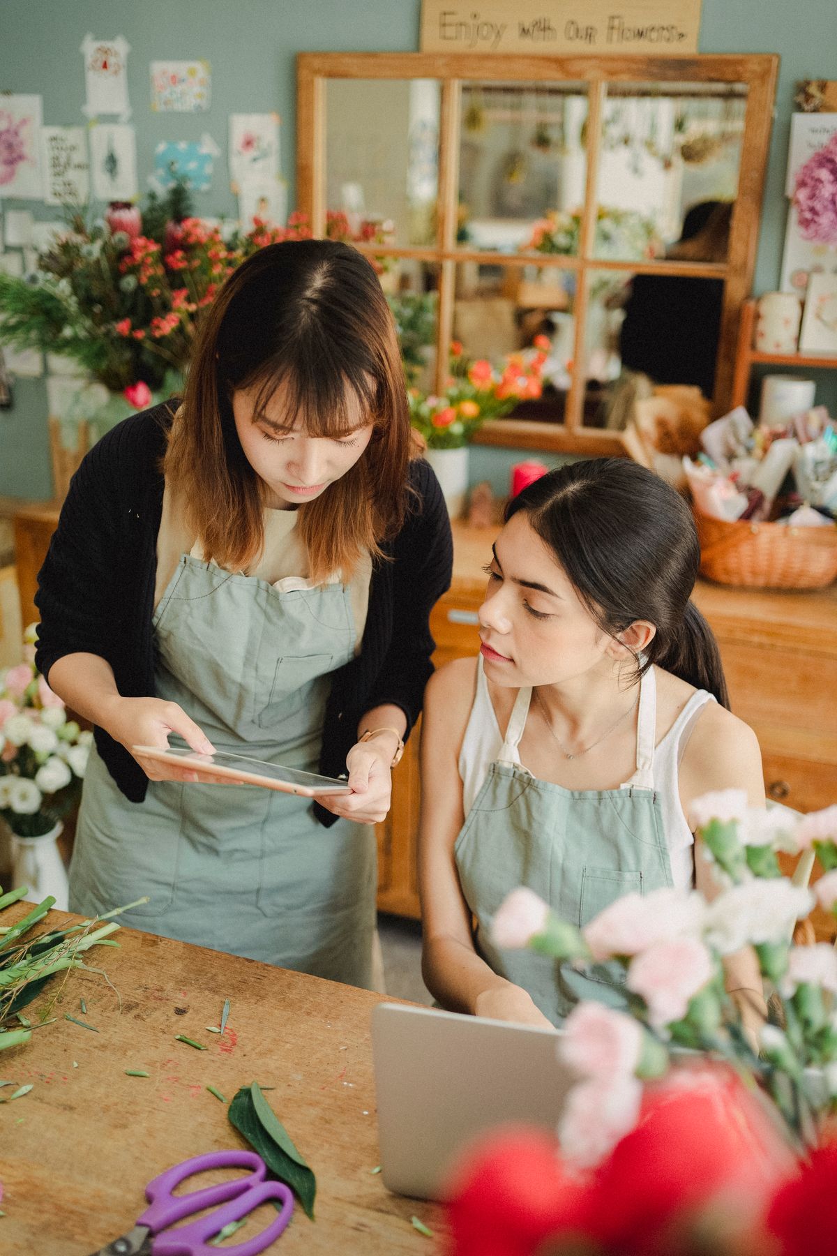 Two florists reviewing content plans together on a tablet in their flower shop